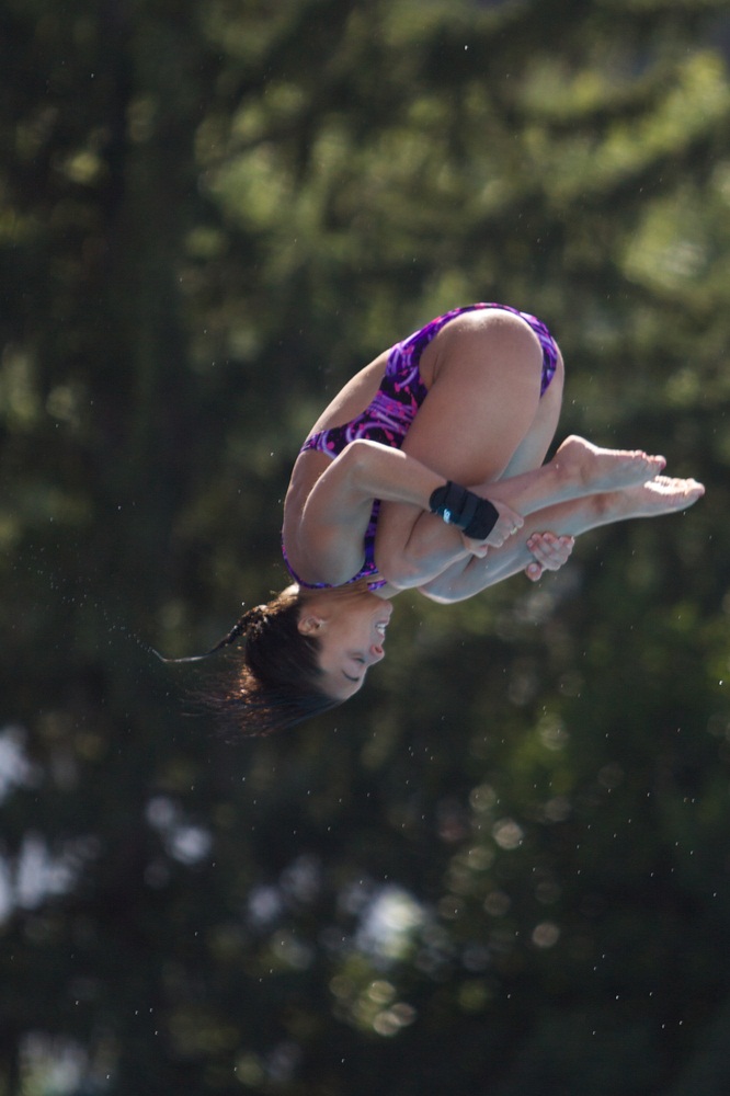 Olympic medalist Meaghan Benfeito executes a high dive in tuck position, pulling her body into a tight ball while somersaulting through the air. Demonstrating proper form, she grabs her shins, pulls her knees to her chest, and points her toes. (Marcello Farina/ Shutterstock)