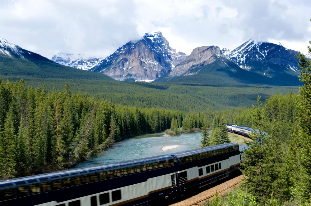 A tourist train rolls through the Canadian Rockies. The best seats on the double-decker passenger cars are on top, where there is a glass-domed roof. (Natalia Bratslavsky/ Shutterstock)