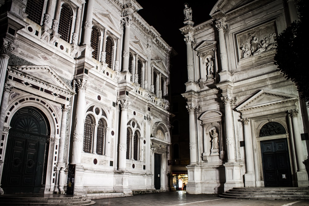 This church and scuola in Venice, Italy, are named for San Rocco, the patron saint of plague victims. The scuola on the left was built in 1485. The rounded arches, fluted columns, and triangular pediments are typical of Renaissance architecture.  (Odor Zsolt/ Shutterstock) 