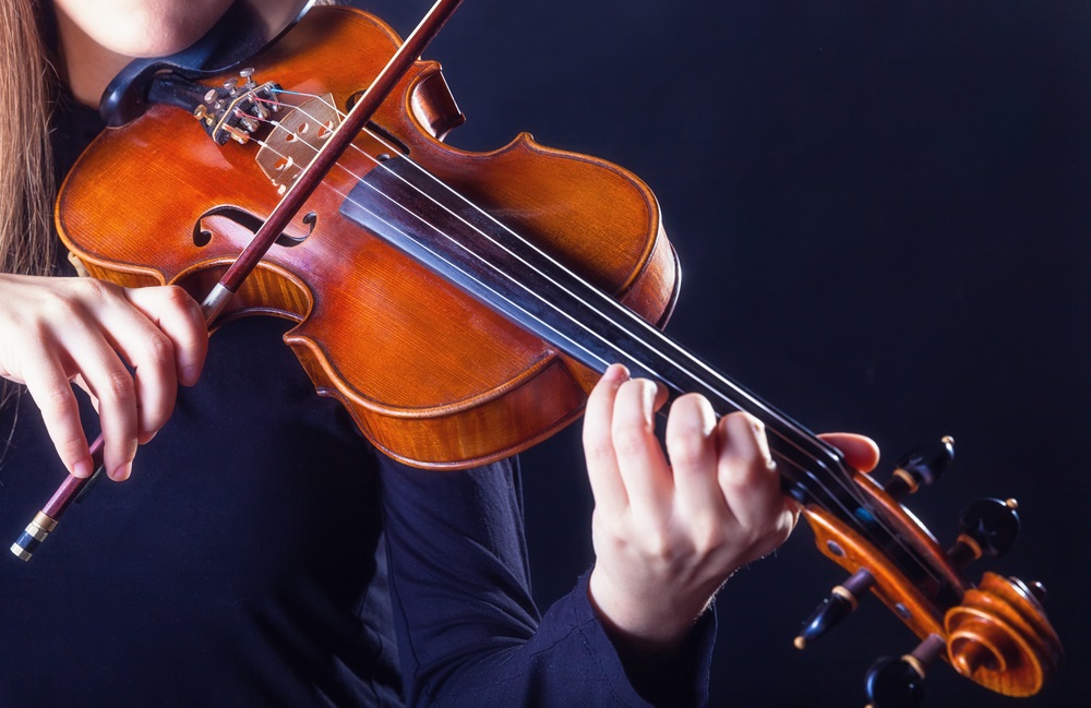 Drawing a bow across a violin’s strings causes them to vibrate. But the vibrations of the strings aren’t strong enough to create very loud or musical sounds. The violin is built so the vibrations from the strings travel through the bridge (shown just above the bow) to the body of the violin. The body of the violin is a sound box and it vibrates, too, creating a rich, round sound and amplifying it.  (Artem Furman/ Shutterstock) 