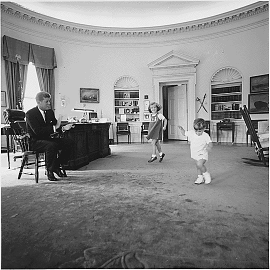 JFK’s children, Caroline and John Jr., play in the Oval Office at the White House. (U.S. National Archives)